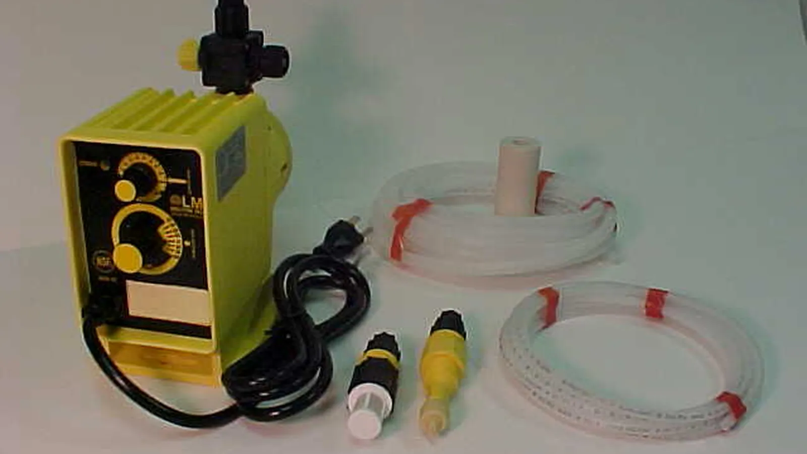 Yellow metering pump with suction tubing, foot valve and fittings laid out for a calibration check