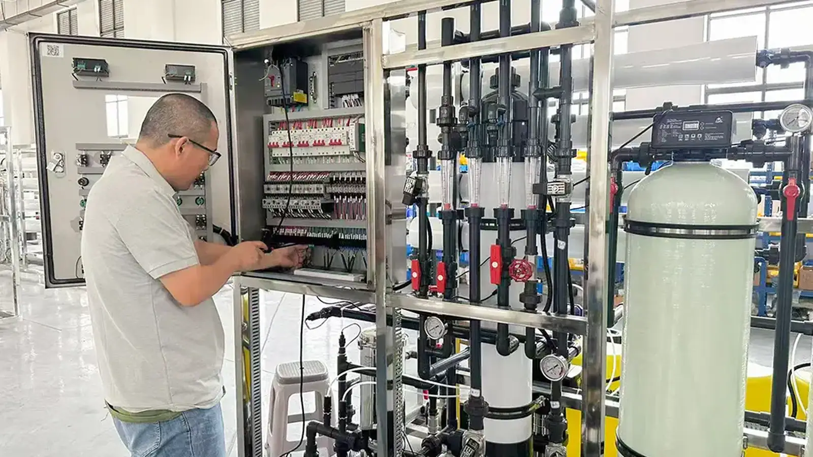 Technician inspecting the control panel of a dosing system with flow meters and tanks