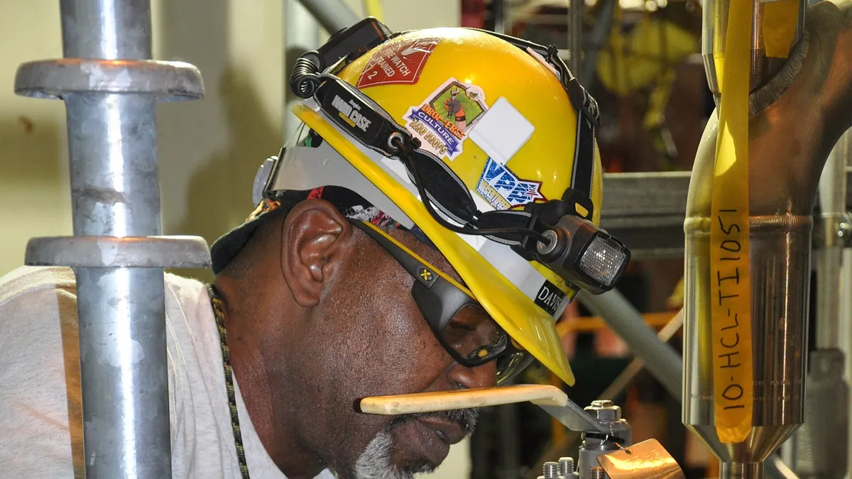 Maintenance worker servicing stainless process piping with valves