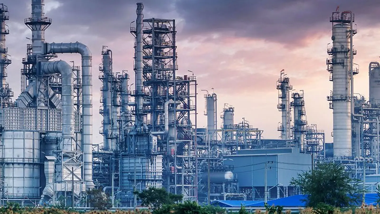 Chemical processing plant with distillation columns and pipe racks at dusk